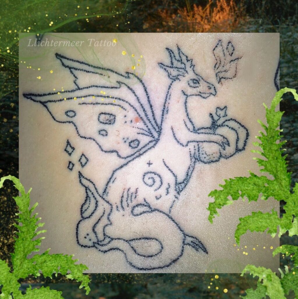 Handpoked energetisches Drachentattoo: tätowierter Schutzdrache der einen Kürbis hält mit Feuerschweif gerahmt von Farn